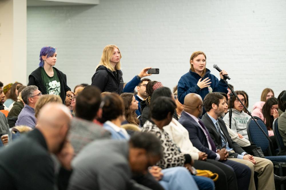 three people standing in line to ask question at microphone